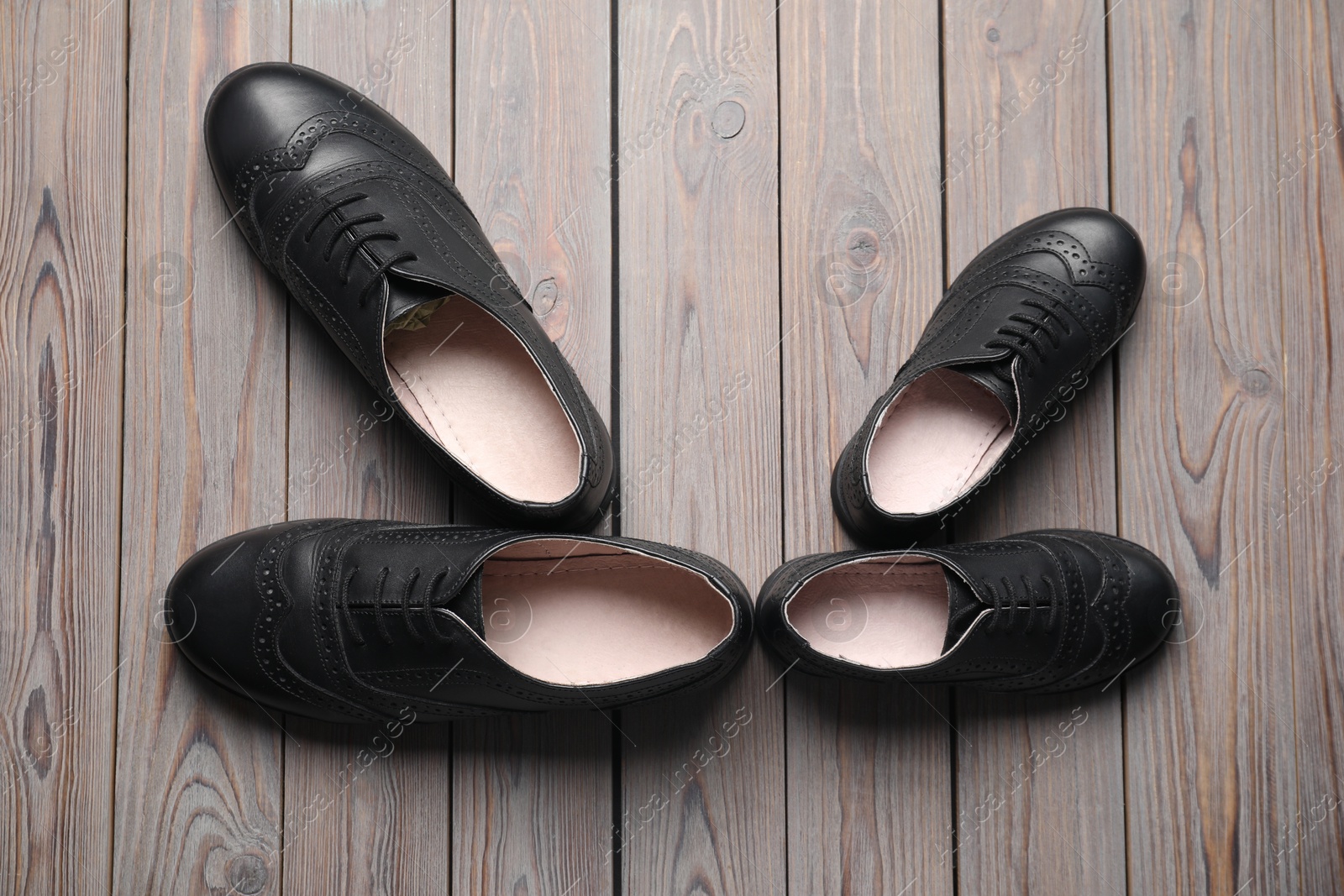 Photo of Big and small shoes on wooden table, flat lay