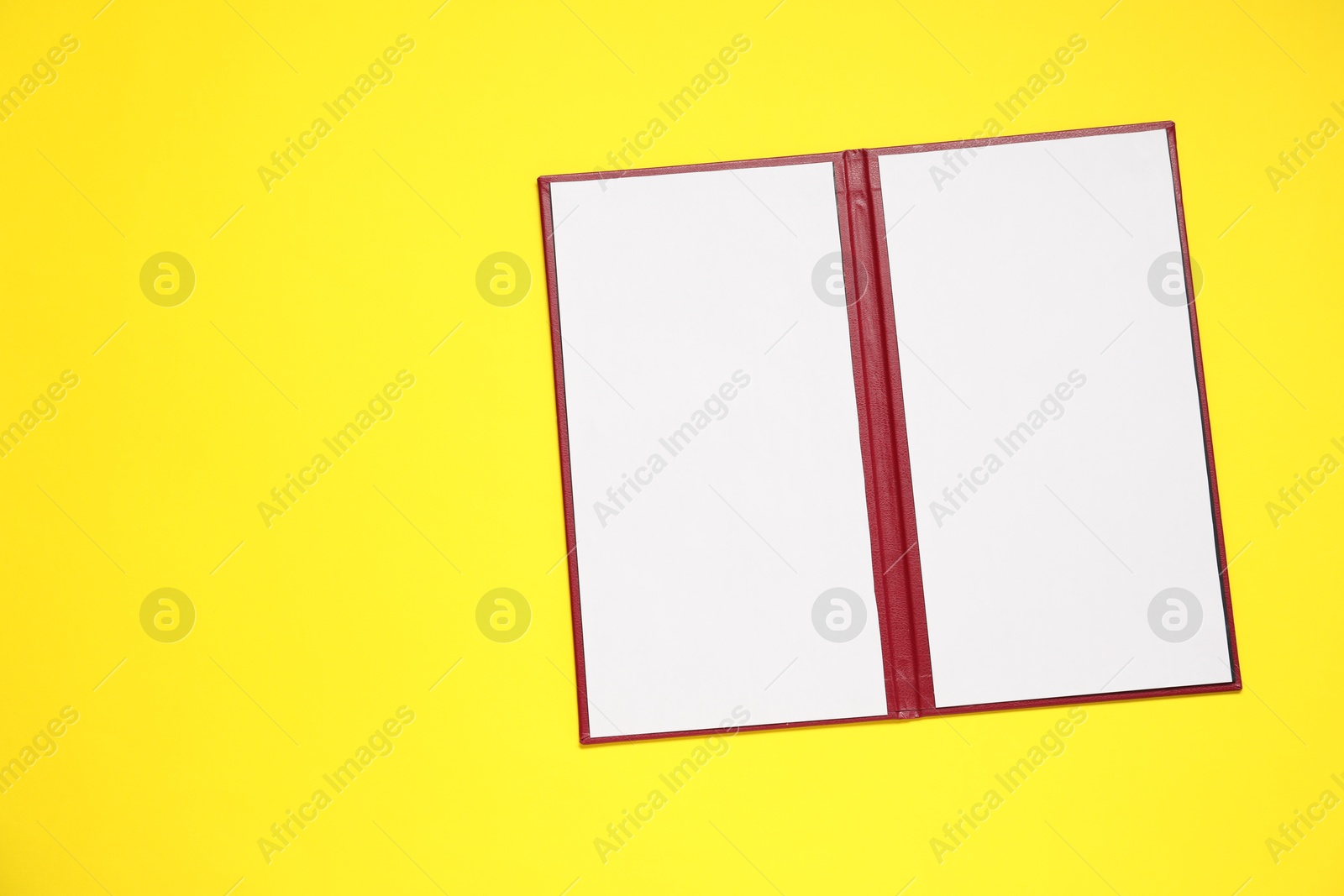 Photo of Hardcover notebook with blank sheets on yellow background, top view. Mockup for design