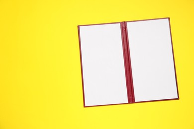 Photo of Hardcover notebook with blank sheets on yellow background, top view. Mockup for design