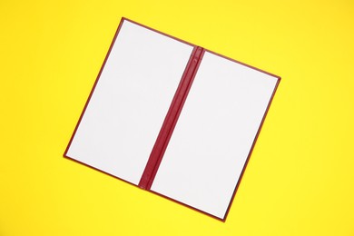 Photo of Hardcover notebook with blank sheets on yellow background, top view. Mockup for design