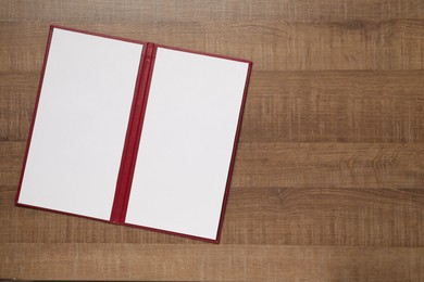 Photo of Hardcover notebook with blank sheets on wooden table, top view. Mockup for design