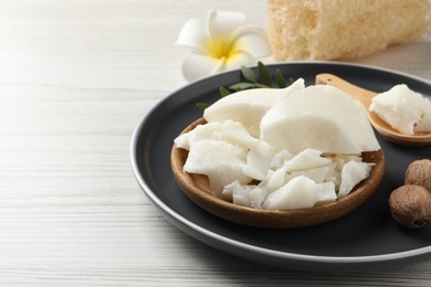 Photo of Natural shea butter, nuts, plumeria flower and loofah sponge on wooden table, space for text