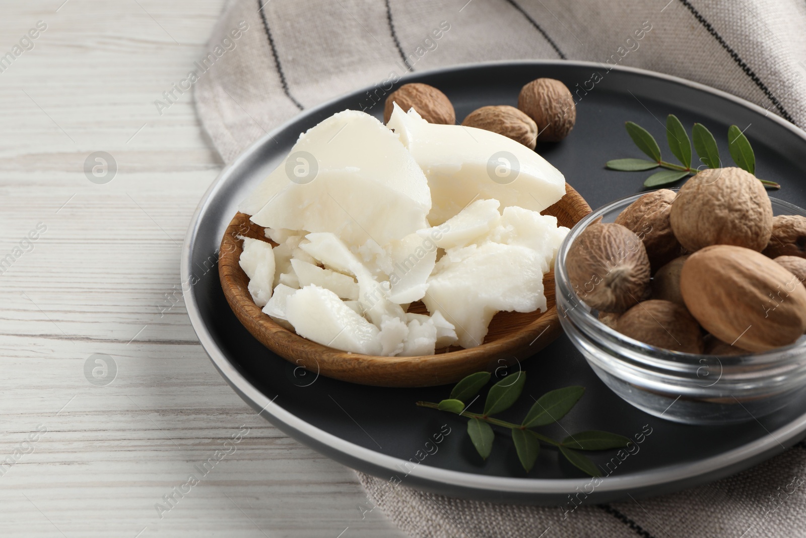 Photo of Natural shea butter, nuts and green leaves on wooden table