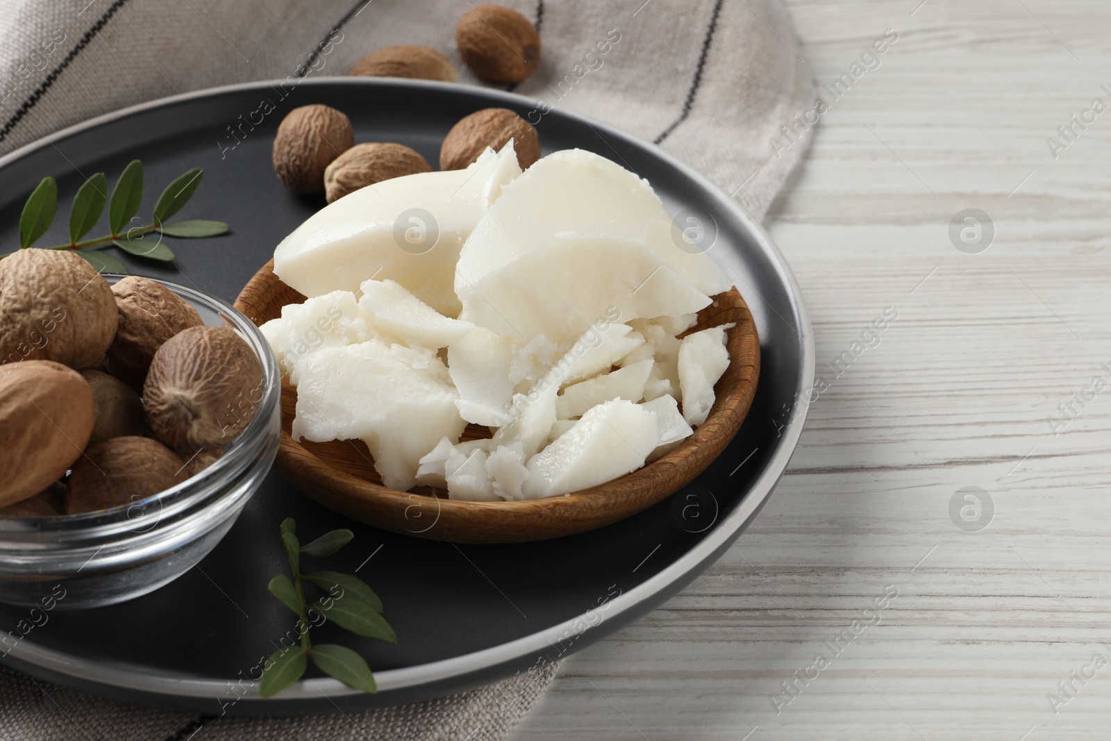 Photo of Natural shea butter, nuts and green leaves on wooden table