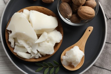 Photo of Natural shea butter, nuts and green leaf on wooden table, top view