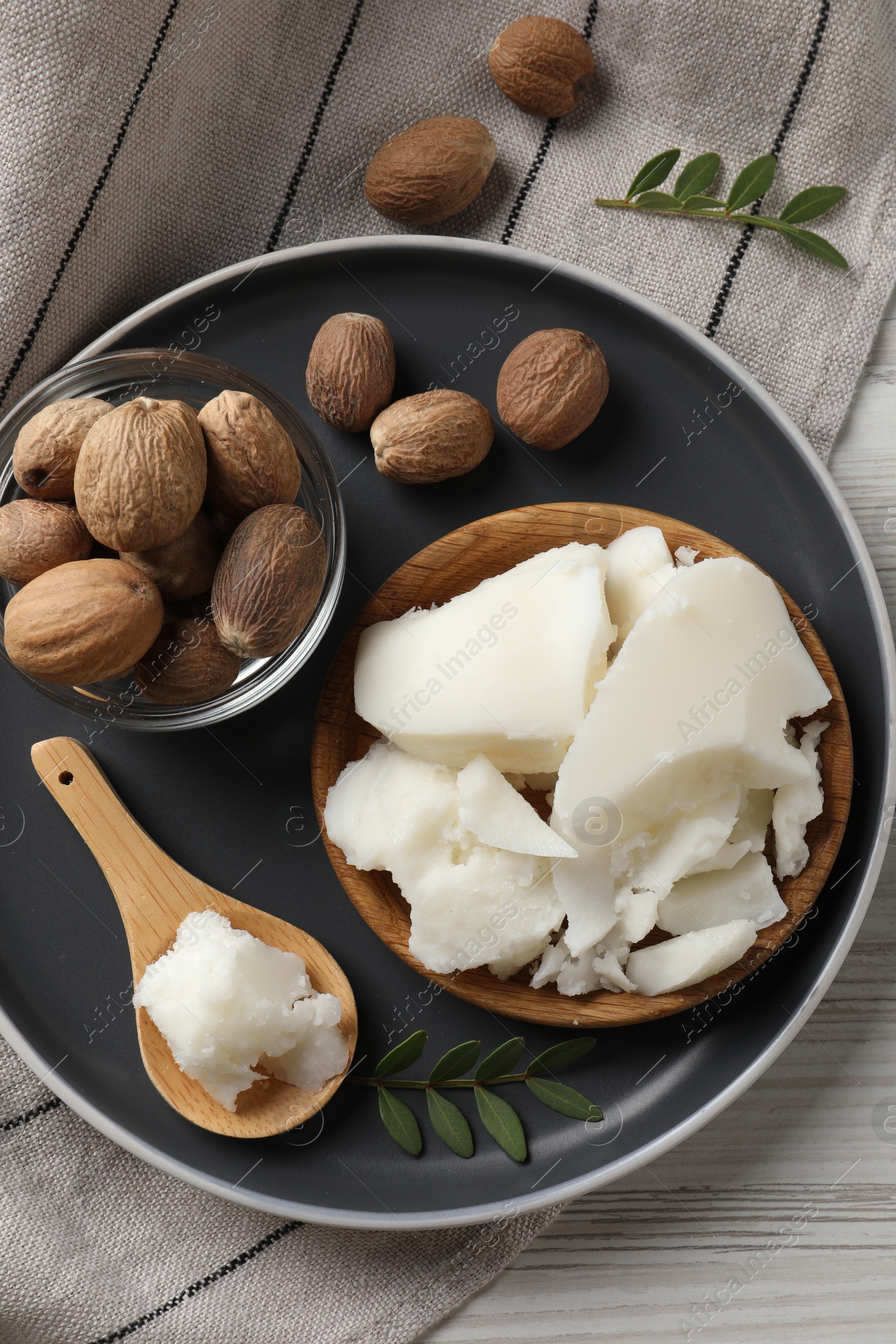 Photo of Natural shea butter, nuts and green leaves on wooden table, top view