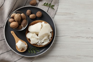 Natural shea butter, nuts and green leaves on wooden table, top view. Space for text