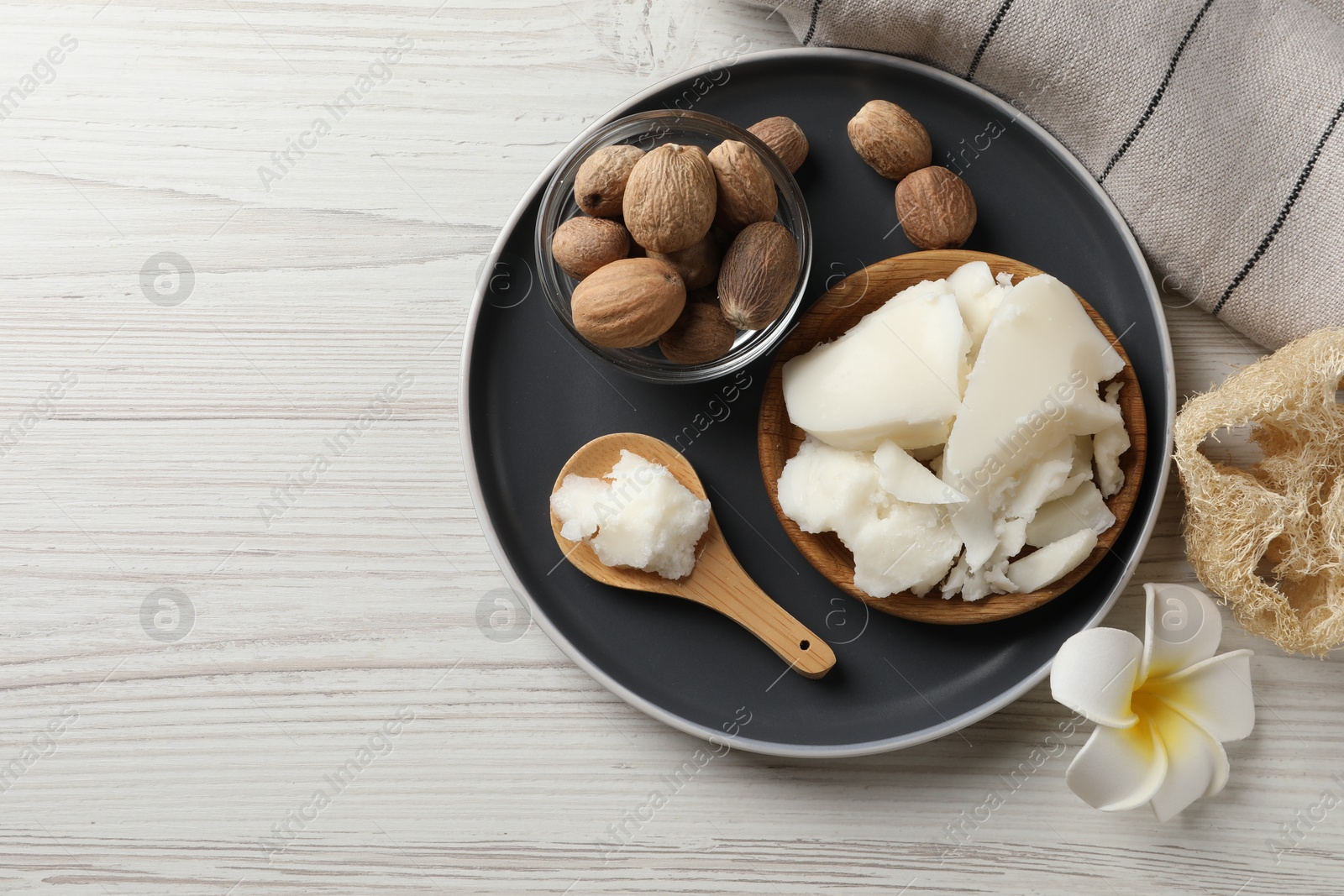 Photo of Natural shea butter, nuts, plumeria flower and loofah on wooden table, top view. Space for text