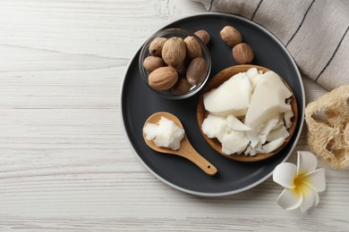 Natural shea butter, nuts, plumeria flower and loofah on wooden table, top view. Space for text