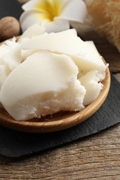 Photo of Natural shea butter, nut and plumeria flower on wooden table