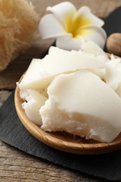 Photo of Natural shea butter, nuts, plumeria flower and loofah sponge on wooden table