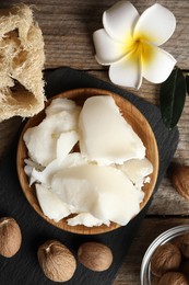 Photo of Natural shea butter, nuts, plumeria flower and loofah sponge on wooden table, top view