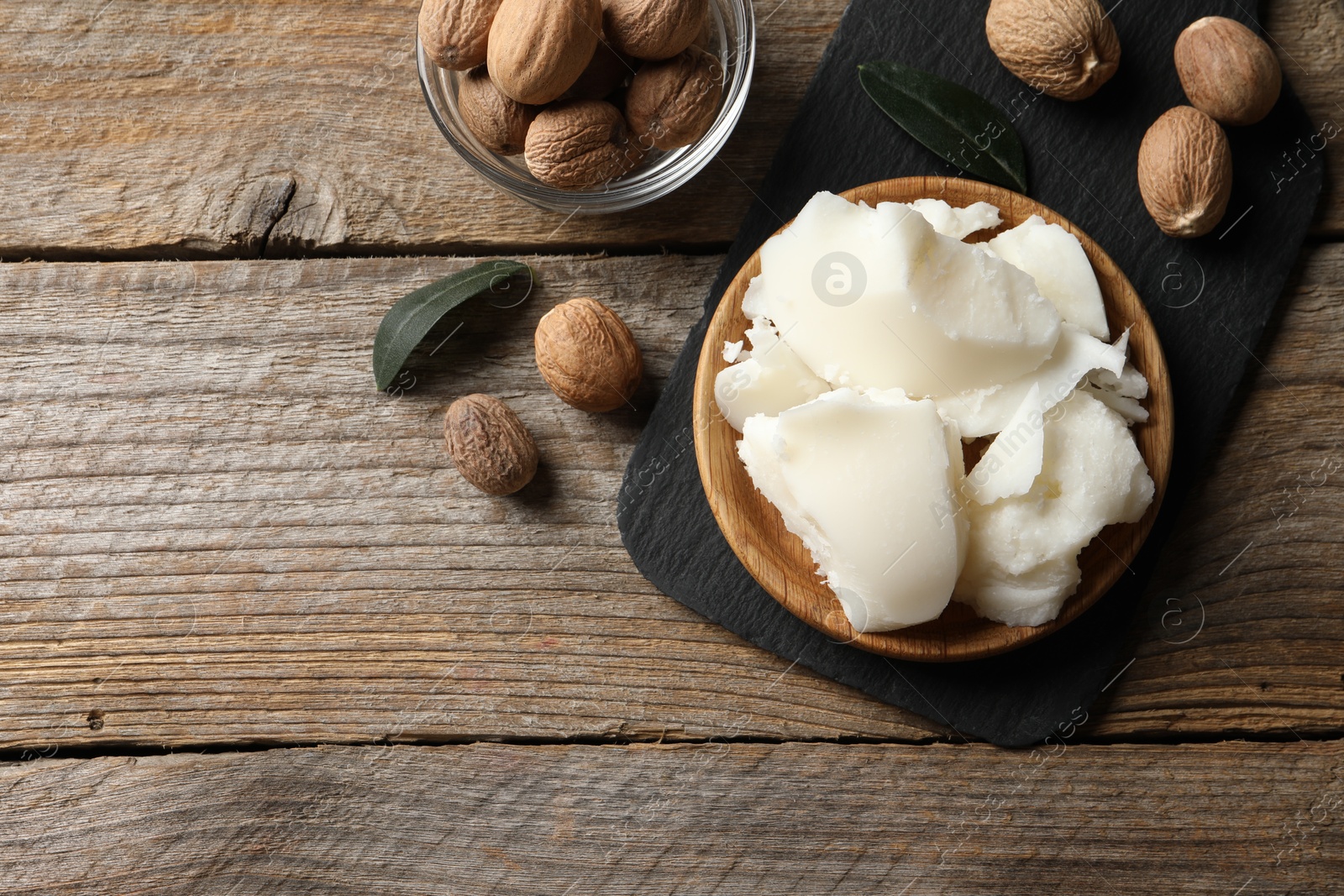 Photo of Natural shea butter and nuts on wooden table, top view. Space for text