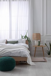 Photo of Stylish living room interior with bed, bedside table, lamp and houseplants