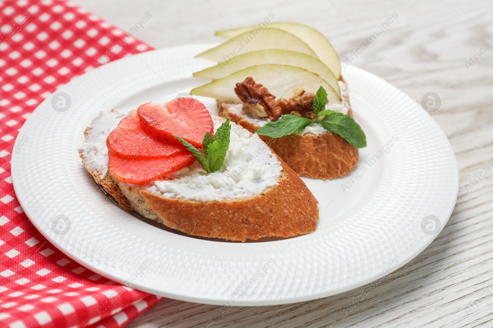 Photo of Delicious bruschettas with fresh ricotta (cream cheese), strawberry, mint and pear on wooden table, closeup