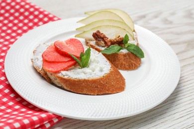 Delicious bruschettas with fresh ricotta (cream cheese), strawberry, mint and pear on wooden table, closeup