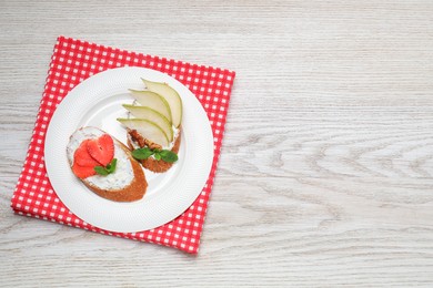 Photo of Delicious bruschettas with fresh ricotta (cream cheese), strawberry, mint and pear on wooden table, top view. Space for text