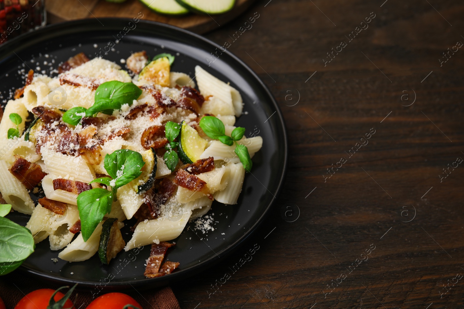 Photo of Tasty pasta with bacon and basil on wooden table, space for text