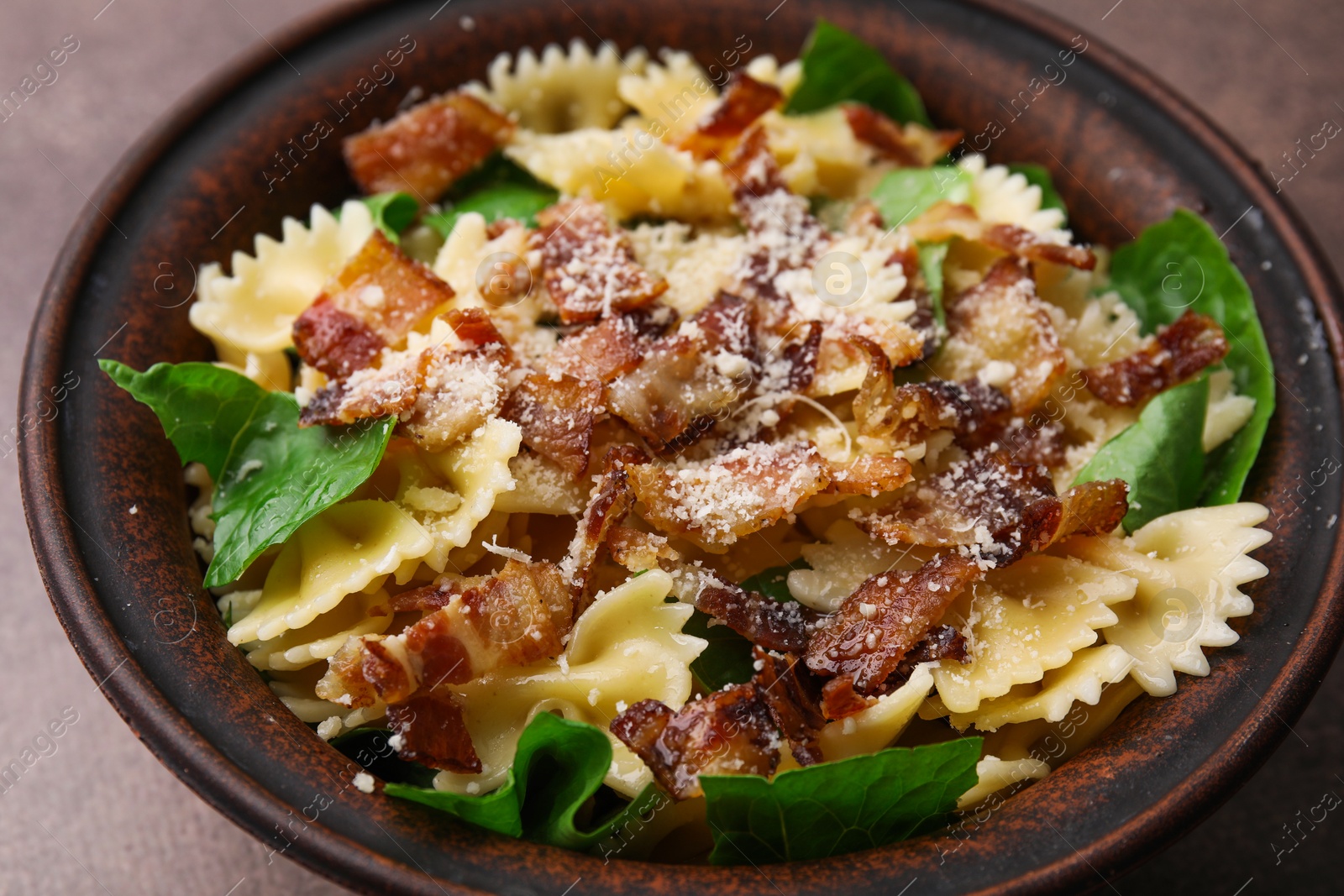 Photo of Tasty pasta with bacon and basil on brown table, closeup