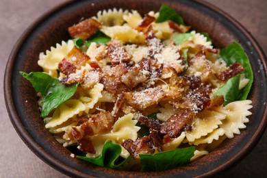 Photo of Tasty pasta with bacon and basil on brown table, closeup