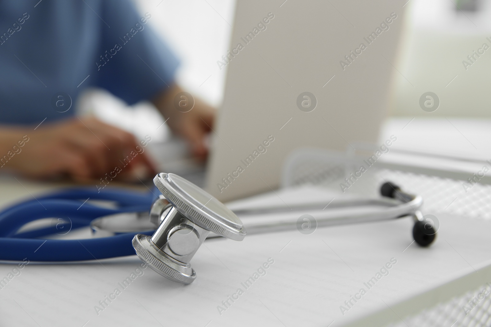 Photo of Doctor at white table in hospital, focus on medical stethoscope