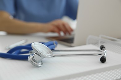 Photo of Doctor at white table in hospital, focus on medical stethoscope