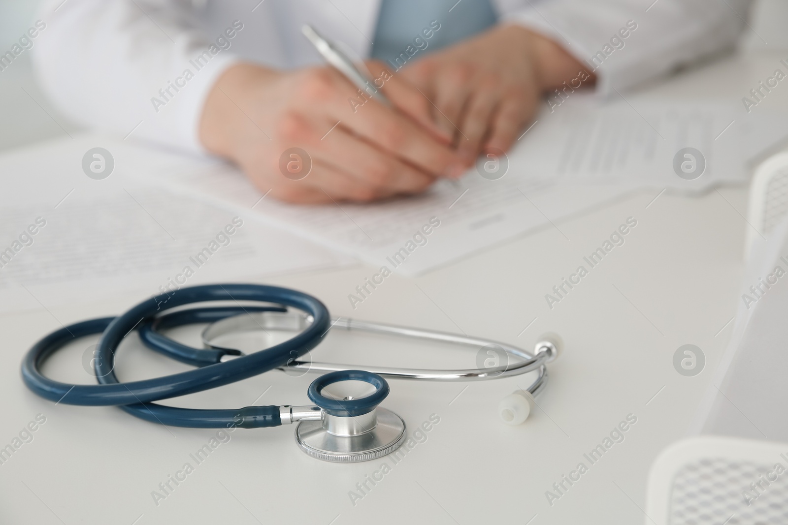 Photo of Doctor at white table in hospital, focus on medical stethoscope