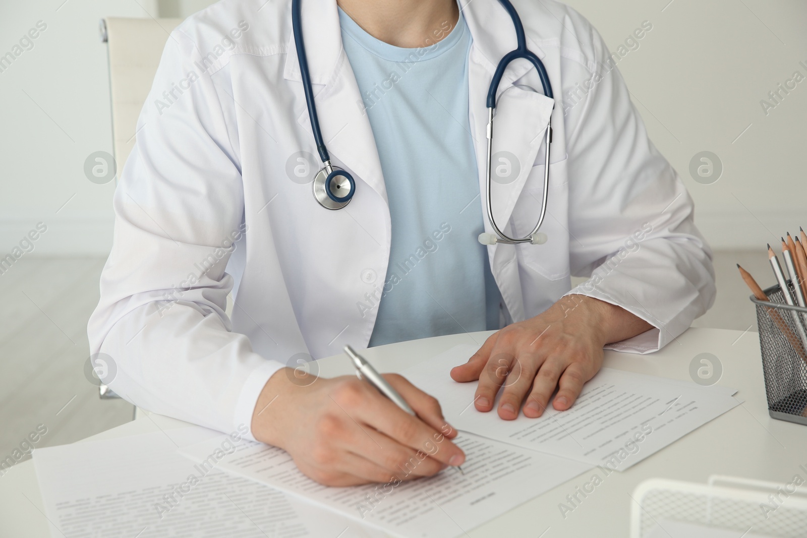 Photo of Doctor with stethoscope at white table in hospital, closeup