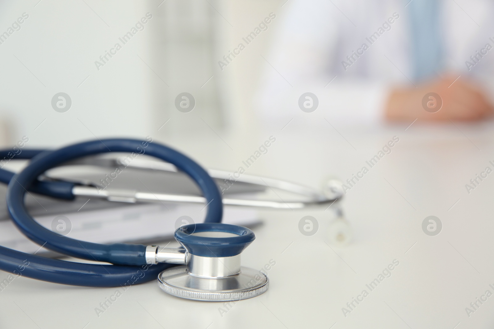 Photo of Doctor at white table in hospital, focus on medical stethoscope