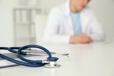 Photo of Doctor at white table in hospital, focus on medical stethoscope