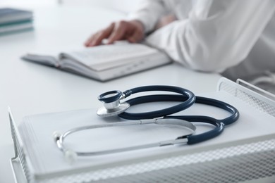 Photo of Doctor at white table in hospital, focus on medical stethoscope