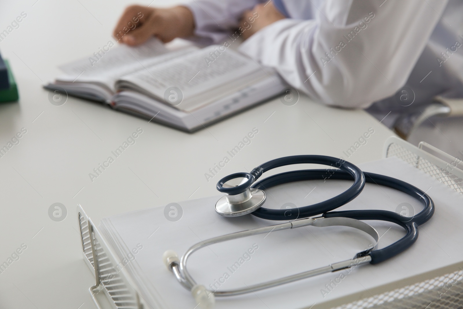 Photo of Doctor at white table in hospital, focus on medical stethoscope