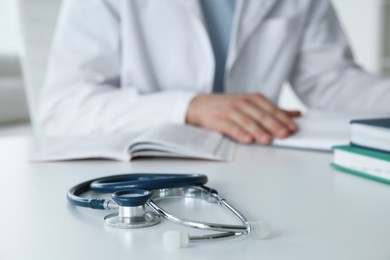 Photo of Doctor at white table in hospital, focus on medical stethoscope