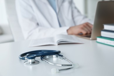 Photo of Doctor at white table in hospital, focus on medical stethoscope