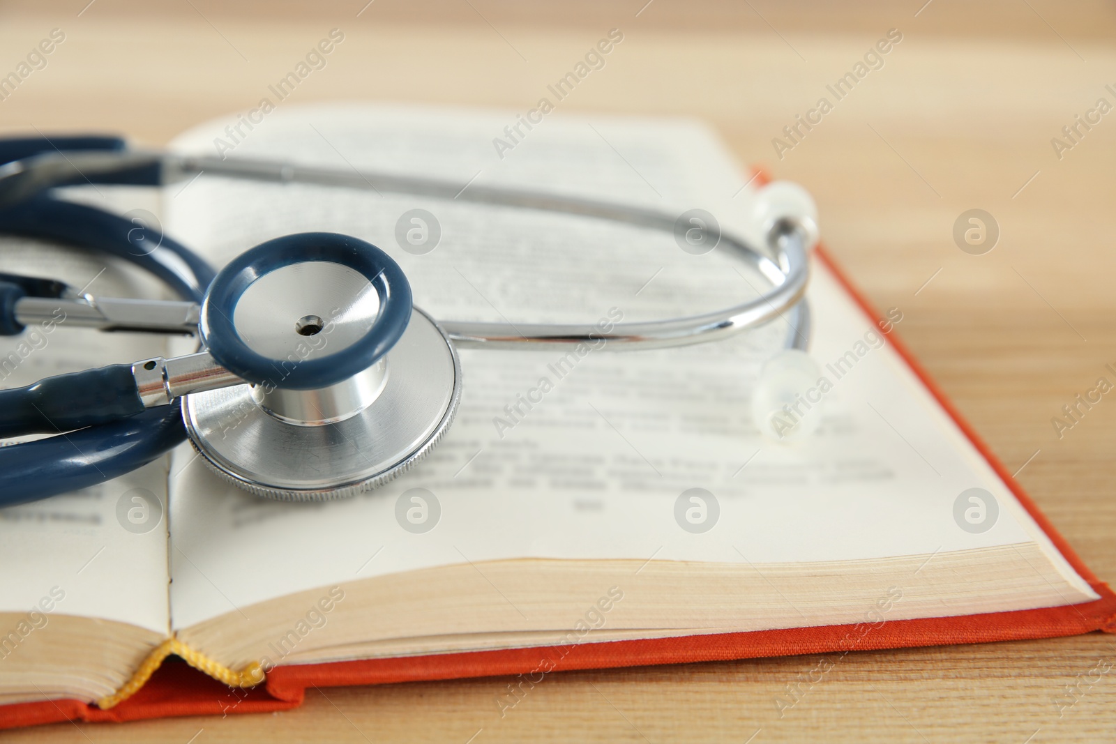 Photo of One new medical stethoscope on wooden table, closeup