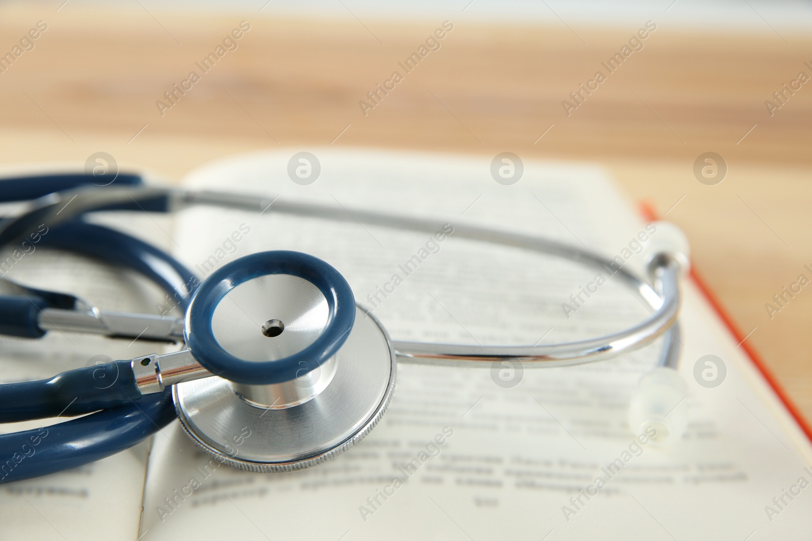 Photo of One new medical stethoscope on wooden table, closeup