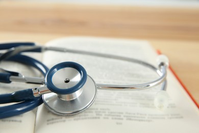 Photo of One new medical stethoscope on wooden table, closeup