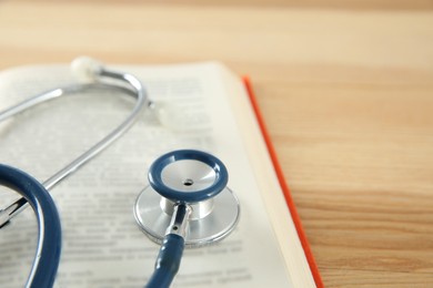 Photo of One new medical stethoscope on wooden table, closeup