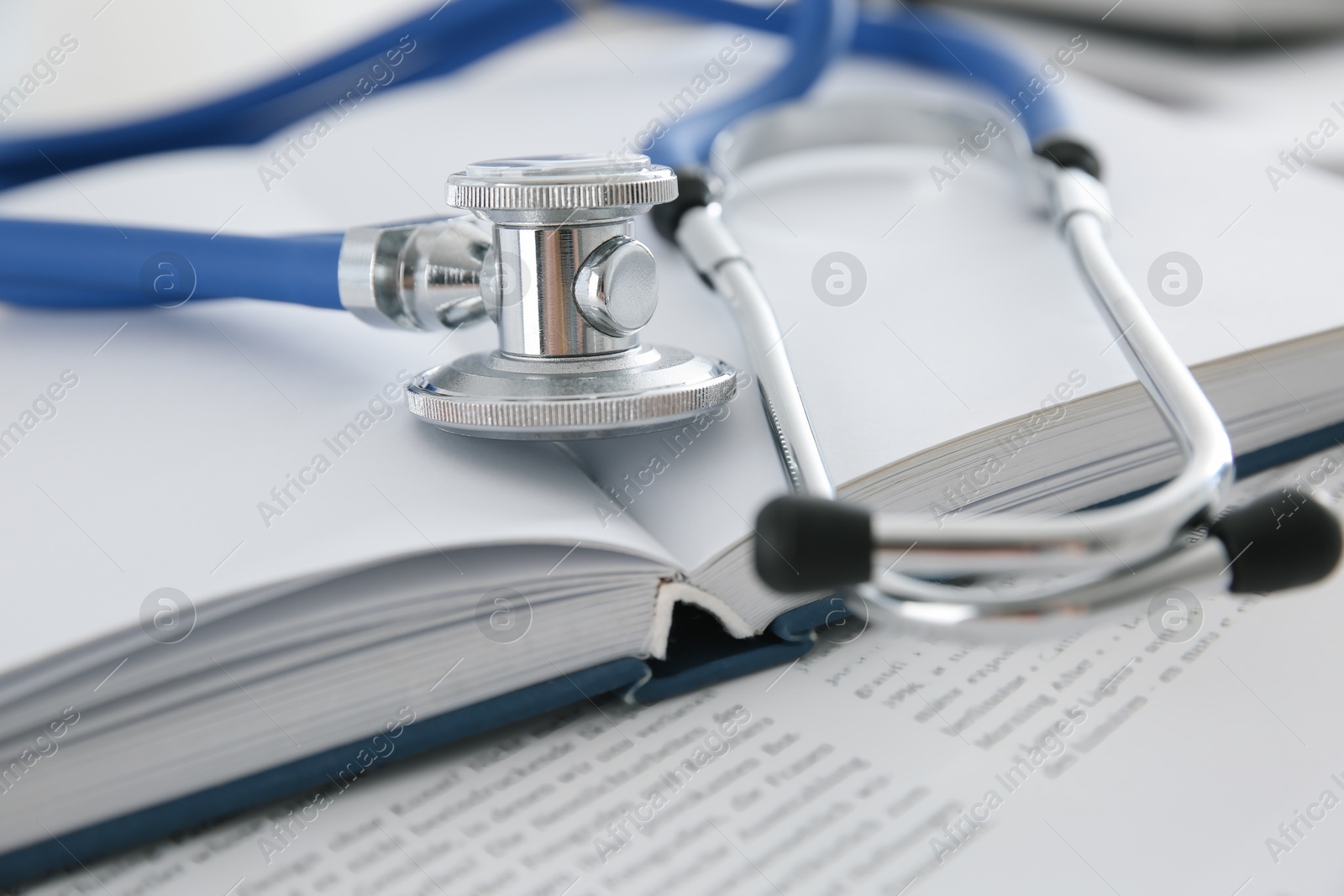 Photo of One new medical stethoscope and books on table, closeup