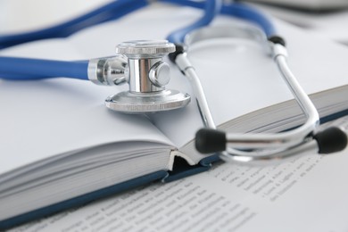 One new medical stethoscope and books on table, closeup