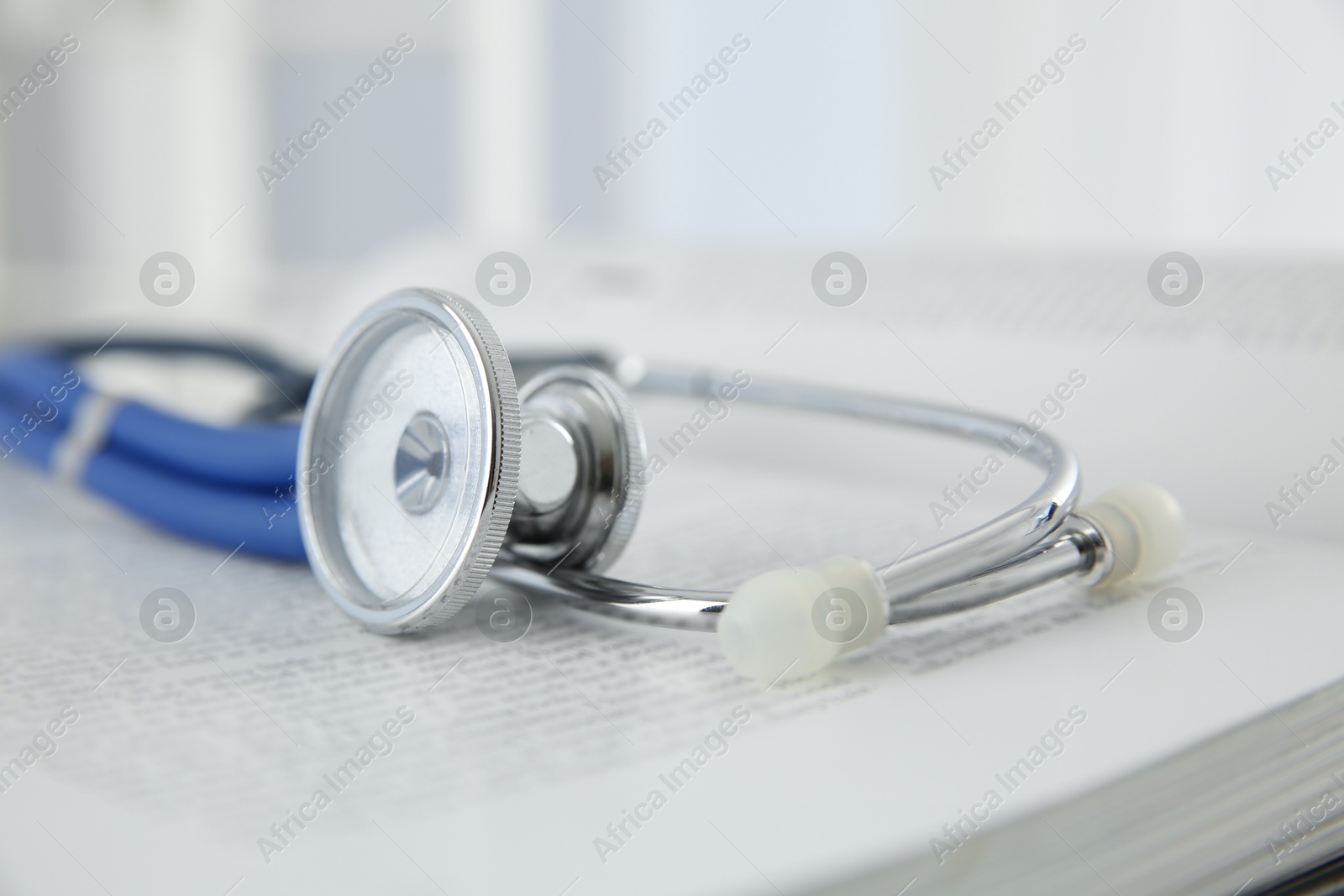 Photo of One medical stethoscope and book on table, closeup