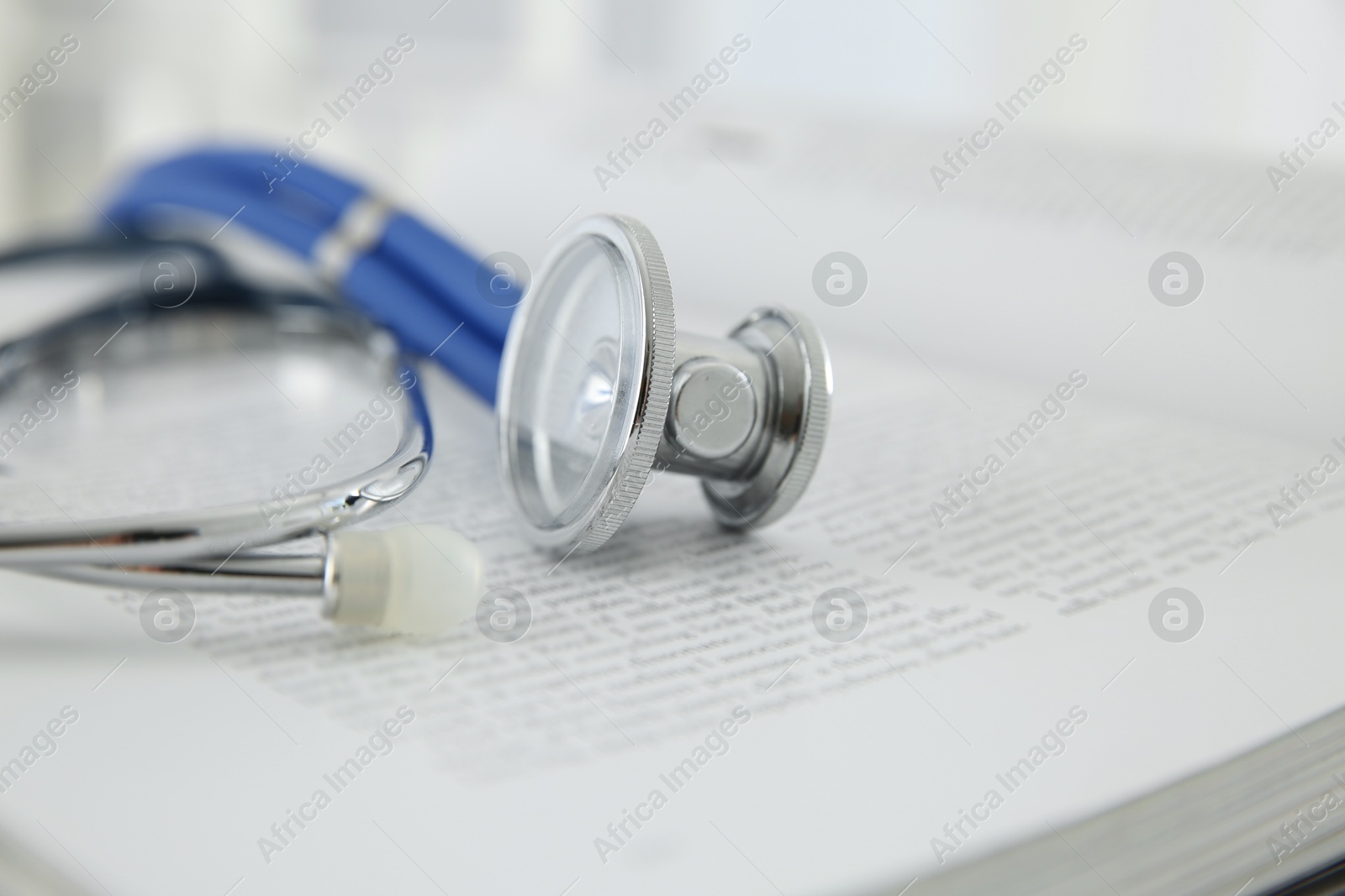 Photo of One medical stethoscope and book on table, closeup