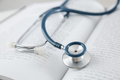 Photo of One medical stethoscope and book on table, closeup