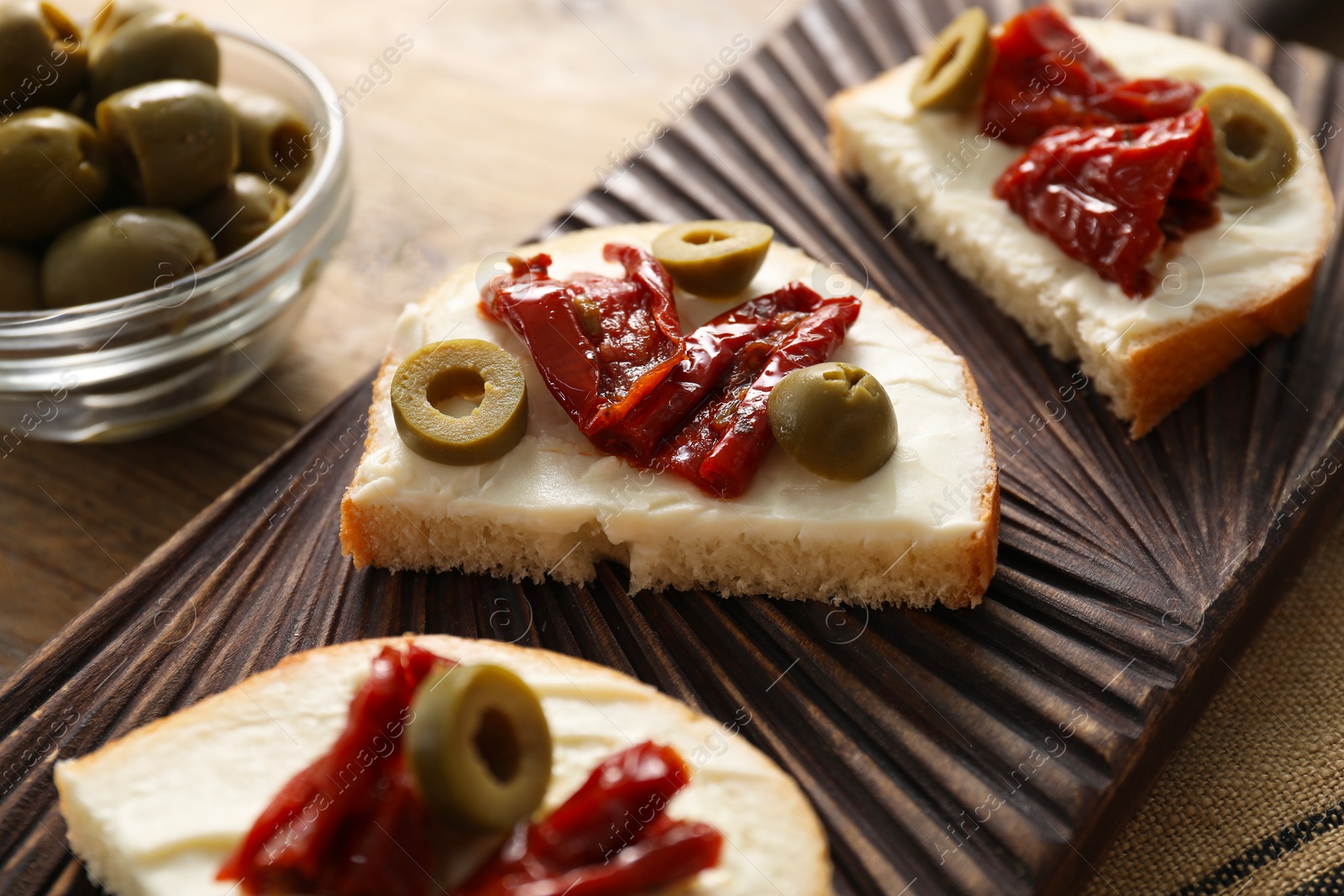 Photo of Delicious bruschettas with ricotta cheese, sun dried tomatoes and olives on table, closeup