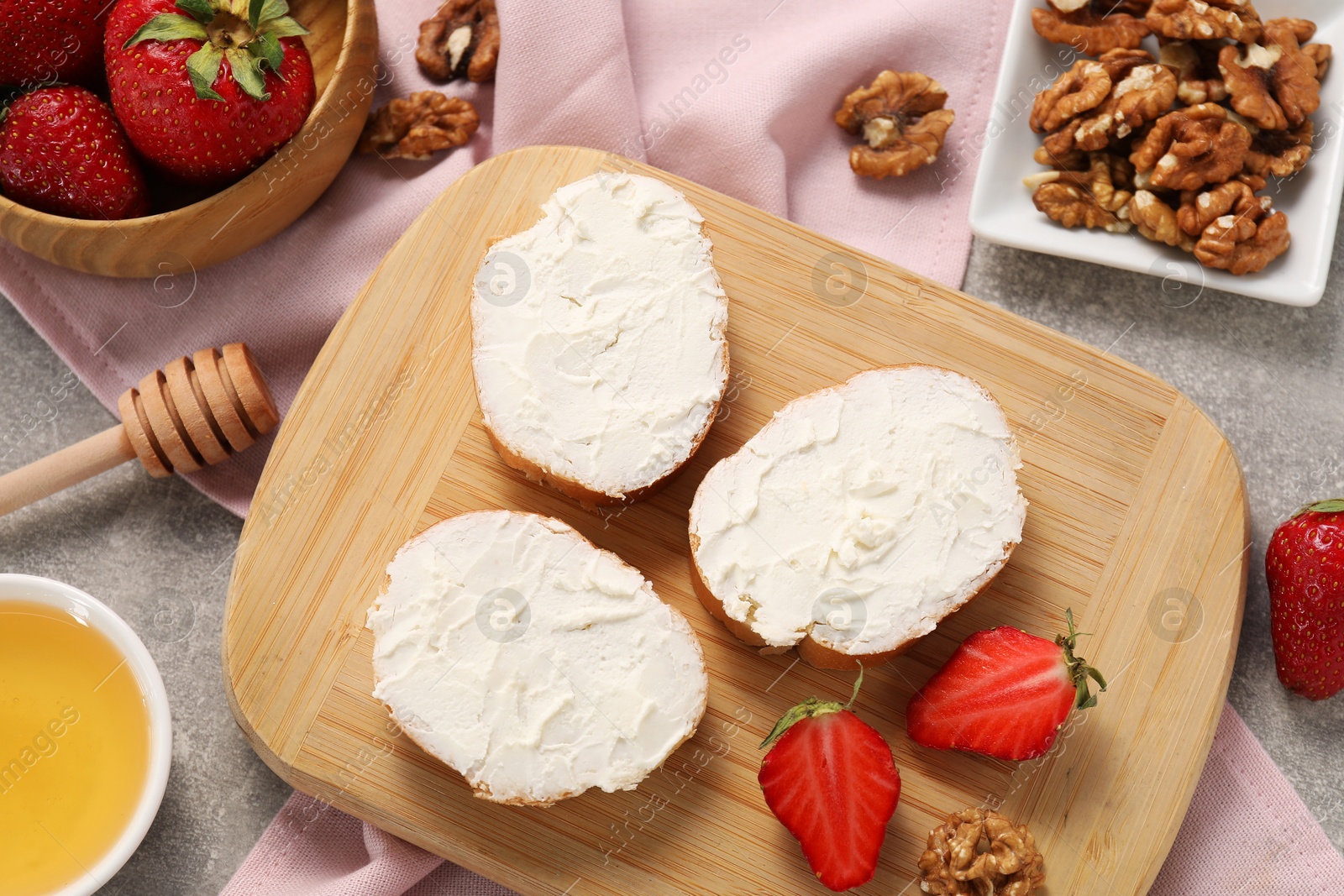 Photo of Delicious bruschettas with ricotta cheese, strawberries, walnuts and honey on grey table, flat lay