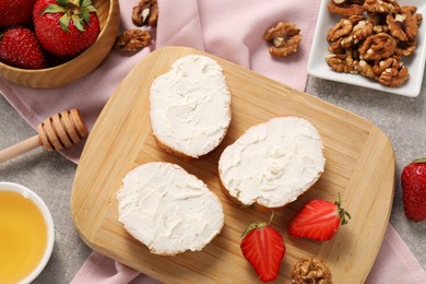 Photo of Delicious bruschettas with ricotta cheese, strawberries, walnuts and honey on grey table, flat lay