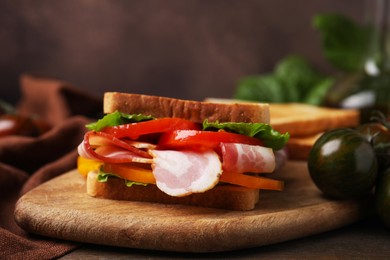 Photo of Tasty sandwich with bacon and tomato on table, closeup