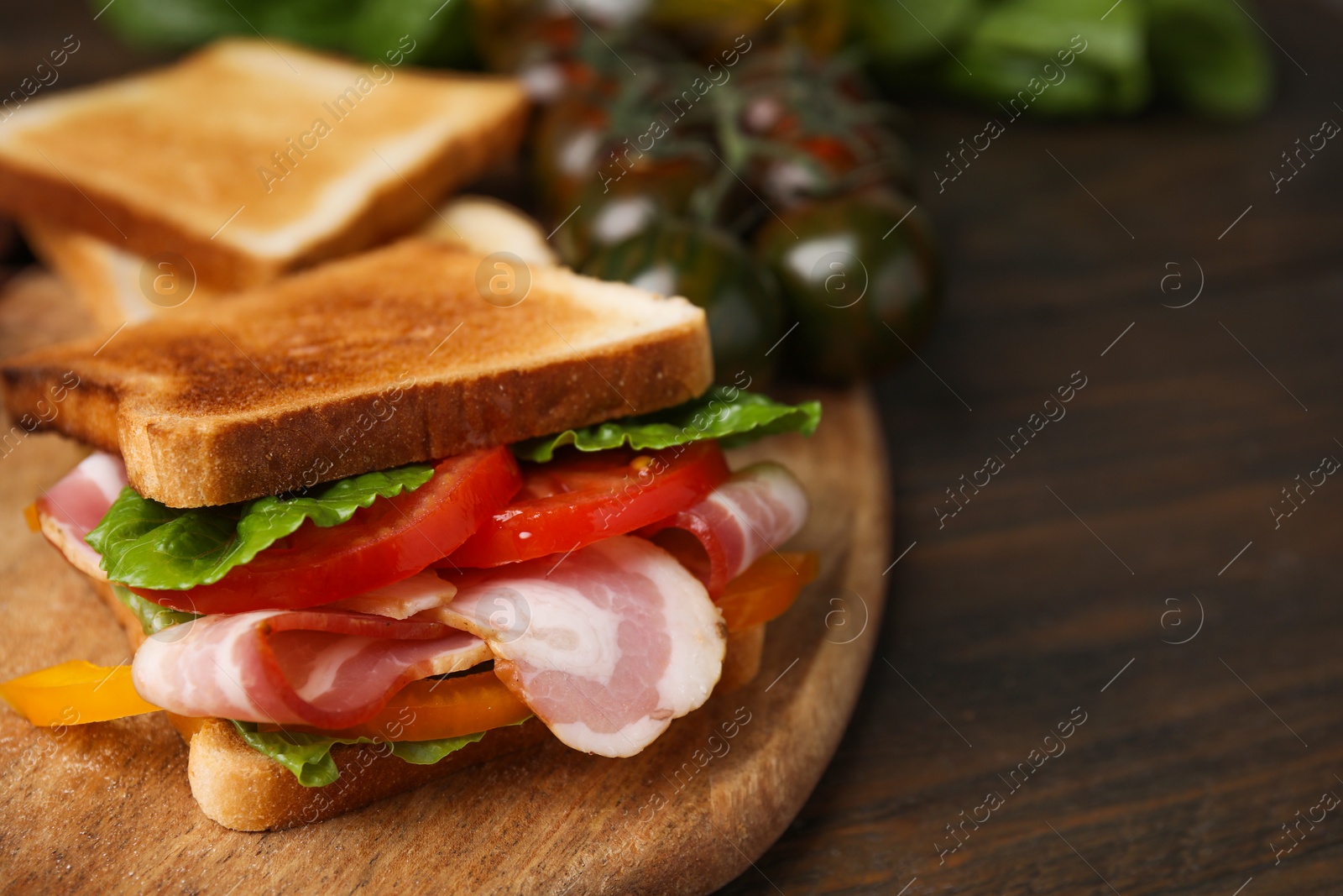 Photo of Tasty sandwich with bacon and tomato on wooden table, closeup. Space for text