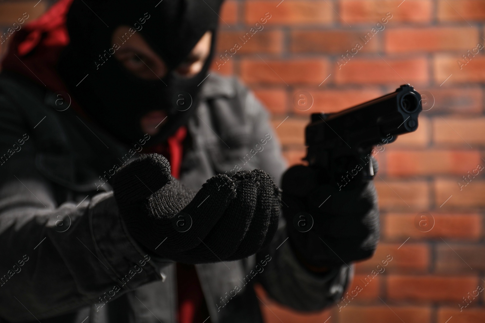 Photo of Dangerous criminal with gun near brick wall, selective focus. Armed robbery