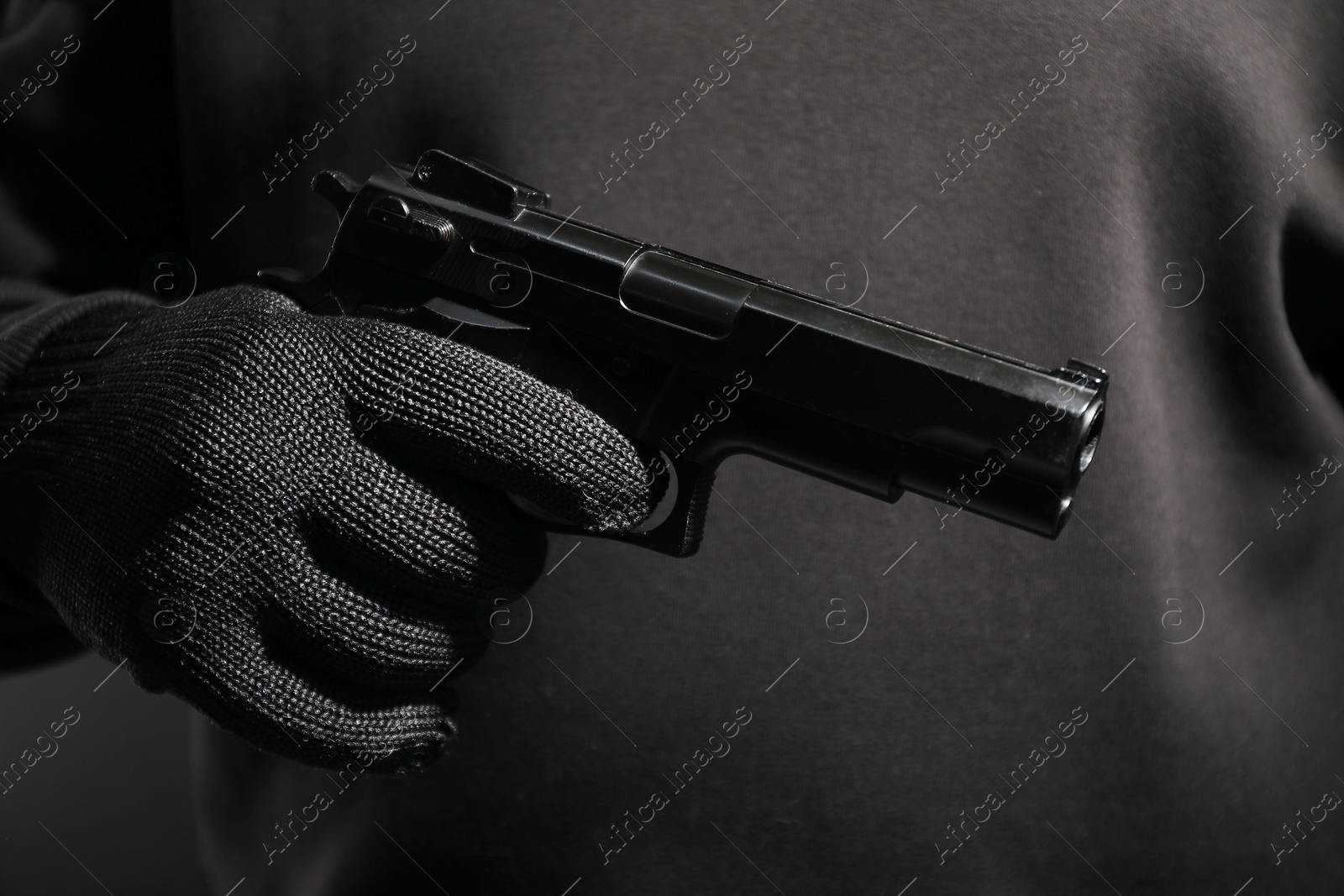 Photo of Dangerous criminal with gun on black background, closeup. Armed robbery